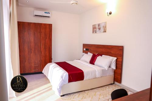 a bedroom with a bed with a wooden headboard at Daviel Elite Apartments in Dodoma