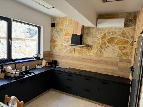 a kitchen with black cabinets and a stone wall at villa efraim read the details from the host for approval in Athens