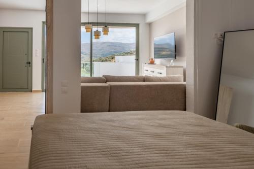 a living room with a couch and a window at Cretan View - Valley & Mountains View Sitia in Áyios Yeóryios