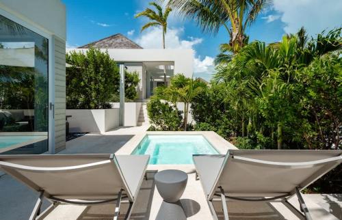 a swimming pool with two chairs and a house at Ocean Dream Studio Blue - Ocean View in Long Bay Hills