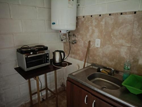 a small kitchen with a microwave and a sink at Hospedaje BellaVilla in Bell Ville