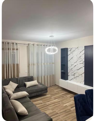 a living room with a couch and a stone wall at Ajans Apartament in Golem