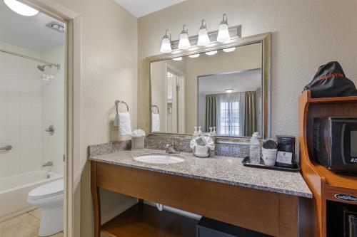 a bathroom with a sink and a toilet and a mirror at Best Western Swiss Clock Inn in Pecos