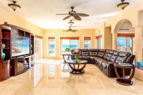 a living room with a leather couch and a television at Breathtaking Chalk Sound Private Pool Sunset Villa in Providenciales