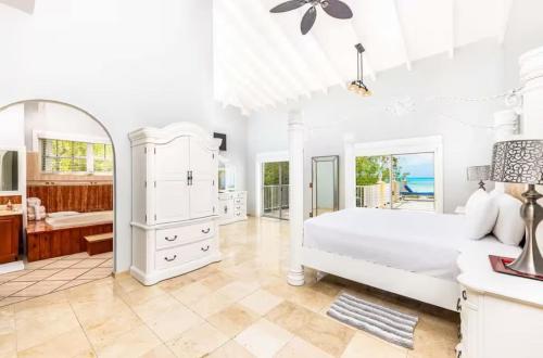 a white bedroom with a bed and a bathroom at Breathtaking Chalk Sound Private Pool Sunset Villa in Providenciales