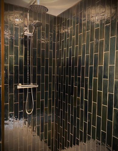 a bathroom with a shower with black tiled walls at St Columbas Boutique BnB in Weobley