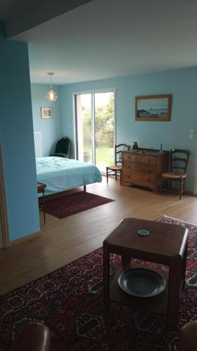 a bedroom with a bed and a table in a room at Chez ALAIN & PATRICK in Vauville