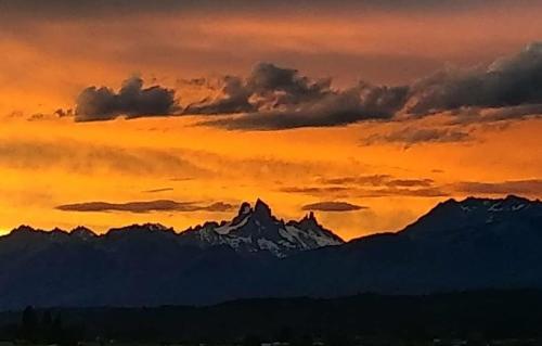 a sunset over a mountain range with snow covered mountains at CASA Los Tres Picos in Cholila