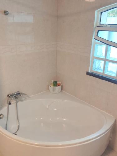 a white bath tub in a bathroom with a window at Oasis Rest in Porto Martins