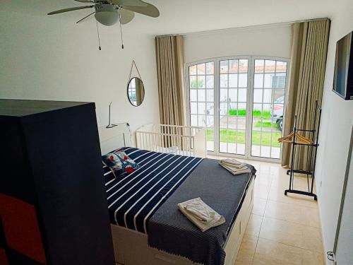 a bedroom with a bed with a blue and white striped sheets at Oasis Rest in Porto Martins