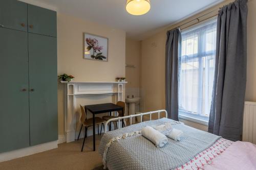 a bedroom with a bed and a table and a window at Clare - Double Room 20 mins walk to centre -Kitchenette Smart TV Shared bathroom in Chesterton