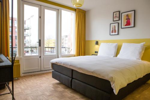 a bedroom with a large bed and a large window at Little Duke Hotel in Den Bosch