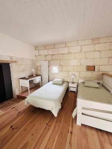 a bedroom with two beds and a brick wall at Le Clos de Tuffeau in Turquant