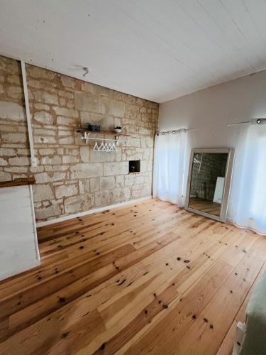 an empty room with a wooden floor and a stone wall at Le Clos de Tuffeau in Turquant