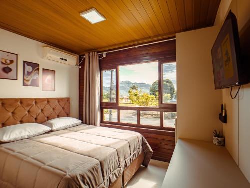 a bedroom with a bed and a large window at Hotel pousada BR 285 in Turvo