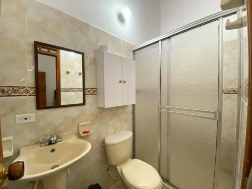 a bathroom with a toilet and a sink and a shower at Hotel Los Ángeles in Buga