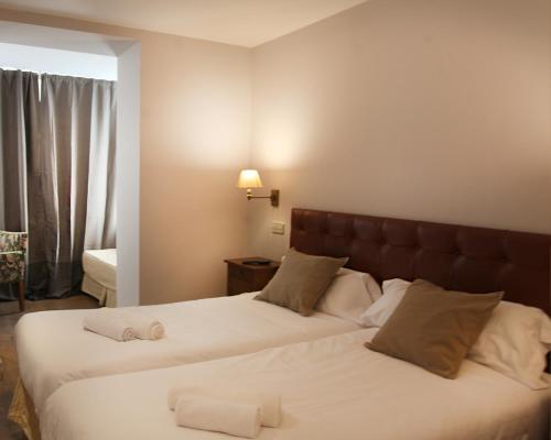 a hotel room with two beds and a window at Hotel Cuéntame La Puebla in Burgos