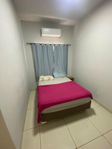 a small bedroom with a bed with a pink blanket at Aconchegante é silencioso in Rio Verde
