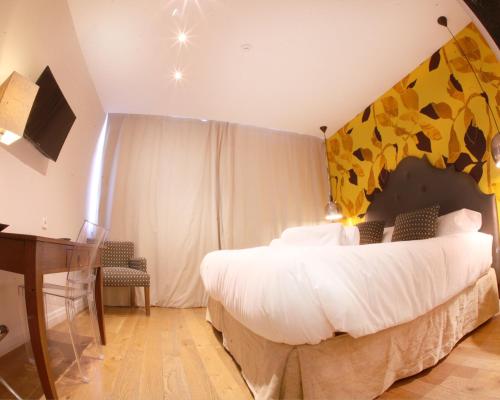 a bedroom with a large bed with a yellow wall at Hotel Cuéntame La Puebla in Burgos