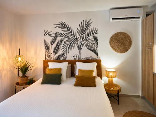a bedroom with a white bed and a palm tree mural at Kalista - Studio Luxueux - Anse Marcel in Saint Martin