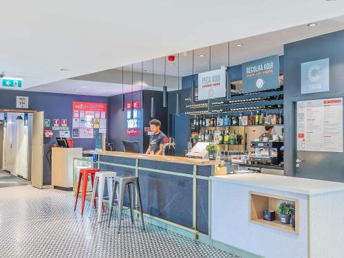a man standing at the counter of a restaurant at Hotel ibis Lisboa Alfragide in Lisbon