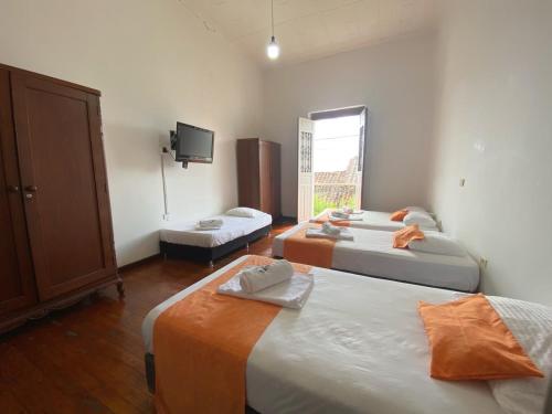 a room with three beds and a tv on the wall at Hotel Los Ángeles in Buga
