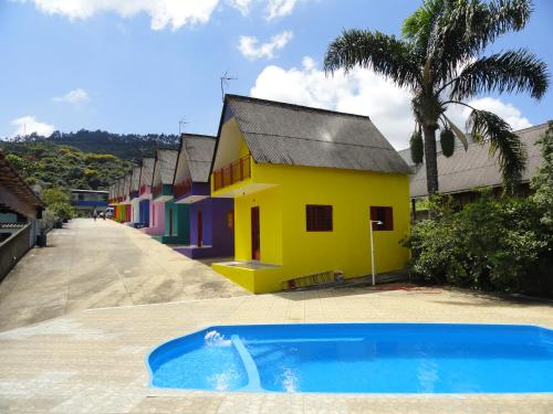 uma casa amarela com uma piscina em frente em Pousada Praia do Sol em Poços de Caldas