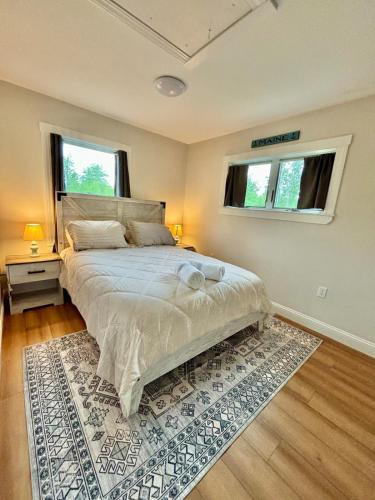 a bedroom with a bed with a rug and two windows at The Happy Hive in Bridgton
