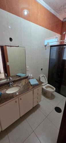 a bathroom with a sink and a toilet and a mirror at Pousada Peruibe in Peruíbe