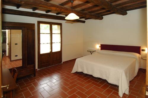 a bedroom with a white bed and a red tile floor at Agriturismo Pian Perugino in Arcidosso