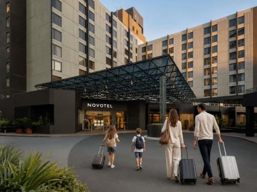 a family walking with their luggage in front of a hotel at Novotel Sydney International Airport in Sydney
