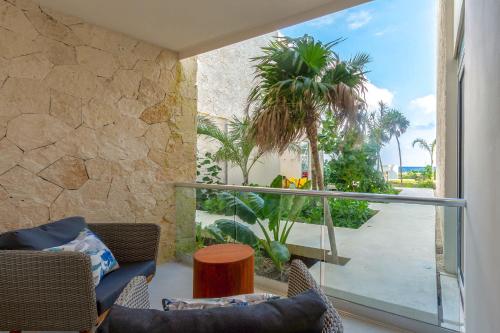 a living room with a view of a palm tree at Chic Beachfront Condo Ocean View Rooftop Pools in Akumal