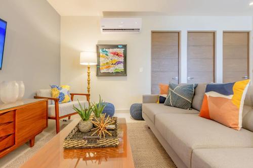 a living room with a couch and a table at Chic Beachfront Condo Ocean View Rooftop Pools in Akumal