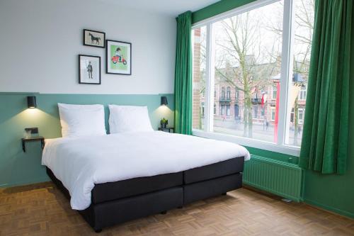 a bedroom with a large bed and a large window at Little Duke Hotel in Den Bosch