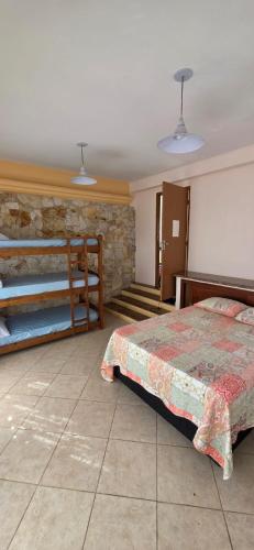 a bedroom with a bed and a stone wall at Pousada Peruibe in Peruíbe