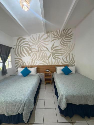 a bedroom with two beds with blue pillows at The Beach Break Hotel El Cocal in Playa San Blas