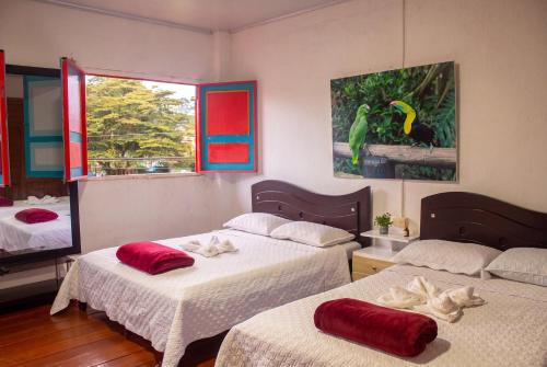 a bedroom with two beds with red pillows on them at Hotel Casa Rosario in Circasia