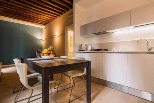 a kitchen and dining room with a wooden table and chairs at Charming Palace Corte del Teatro in Venice