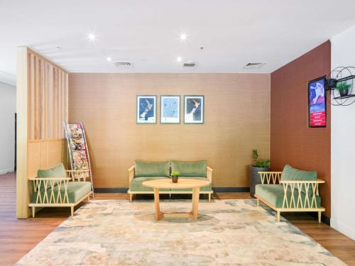 a waiting room with green chairs and a table at ibis Rotorua in Rotorua