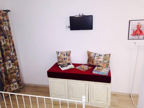 a room with a bench with pillows and a tv at Pensiunea Grădina Ascunsa in Bughea de Jos