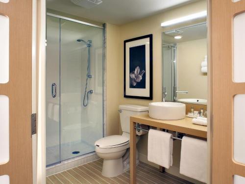 a bathroom with a toilet and a glass shower at Novotel Montréal Aéroport in Dorval