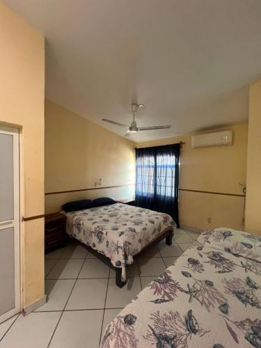 a hotel room with two beds and a window at Las Brisas House, Manzanillo in Manzanillo