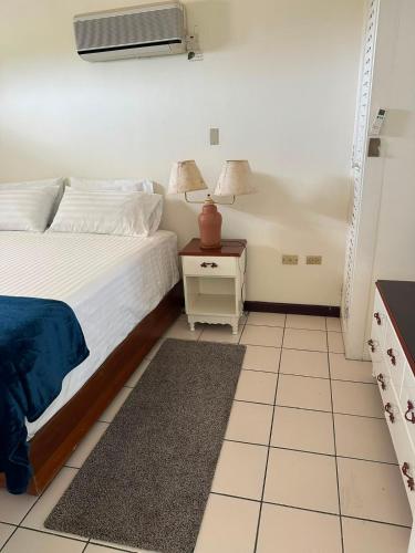 a bedroom with a bed and a night stand with a lamp at A World Away in Montego Bay
