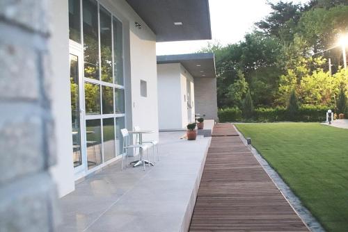 a porch of a white house with a lawn at Gangneung Thebrillant in Gangneung