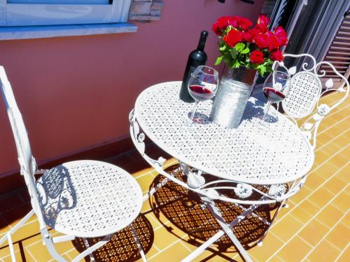 a table with two chairs and a bottle of wine and flowers at Villa Erasi in Fiumicino