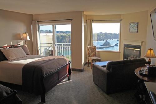 a bedroom with a bed and a living room with a fireplace at North Cliff Hotel in Fort Bragg