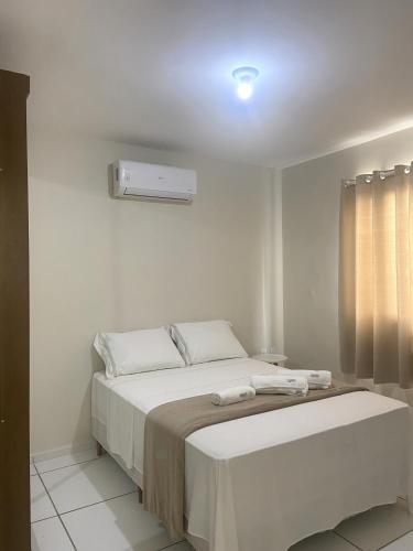 a white bedroom with a bed and a window at Apartamento Flores do Bosque in Garanhuns