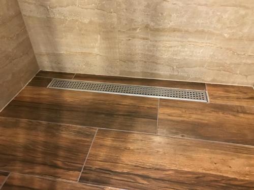 a shower with a wooden floor and a drain at CenterCity Apartments in Prešov