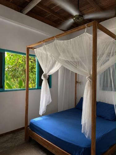 a bedroom with a canopy bed with blue sheets and a window at casa kashiikaii in Palomino