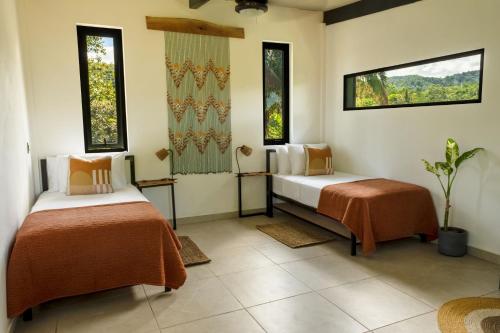 two beds in a room with two windows at Somni Hill in Torio